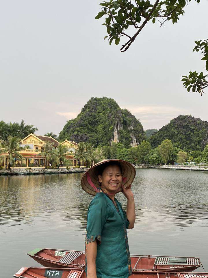 Femme en tenue traditionnelle au bord d'un lac avec des falaises calcaires.