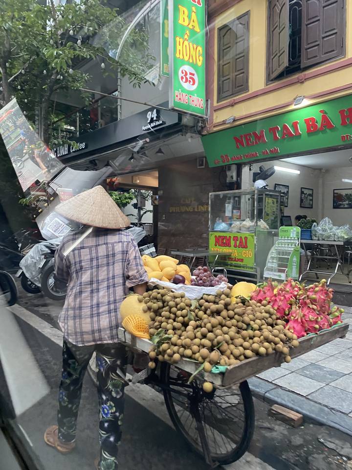 Vendeur ambulant dans une rue animée avec des produits frais.