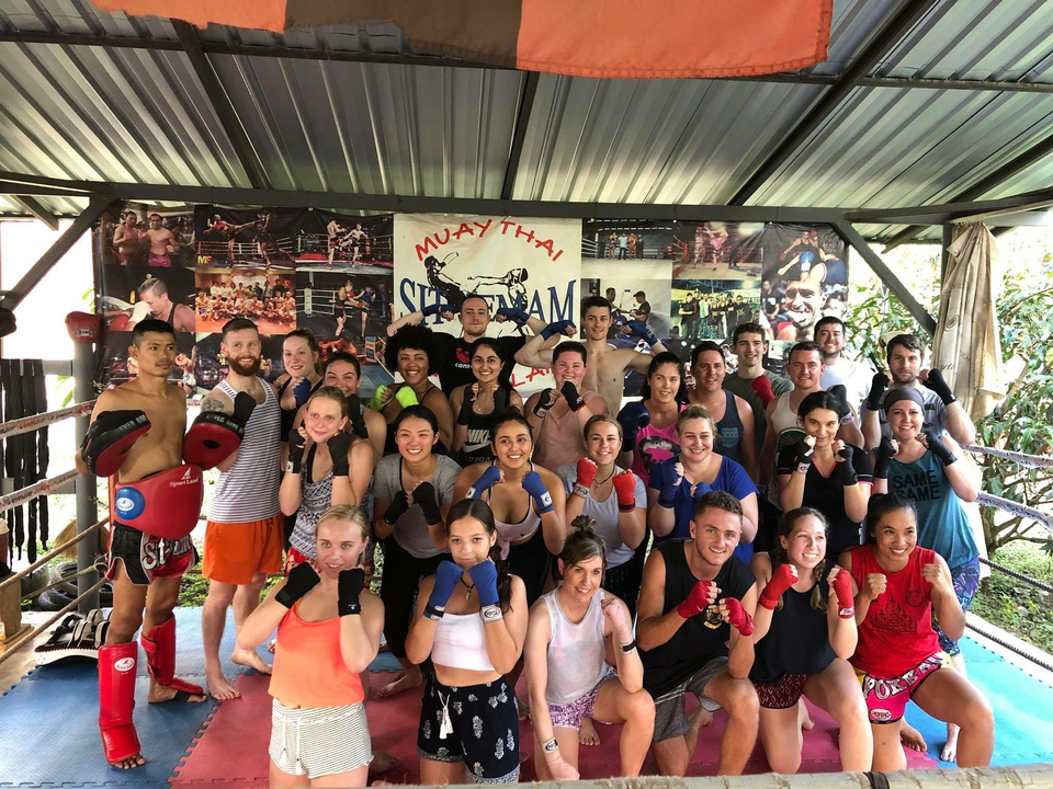 Grand groupe posant avec des gants de boxe dans une salle d'entraînement.