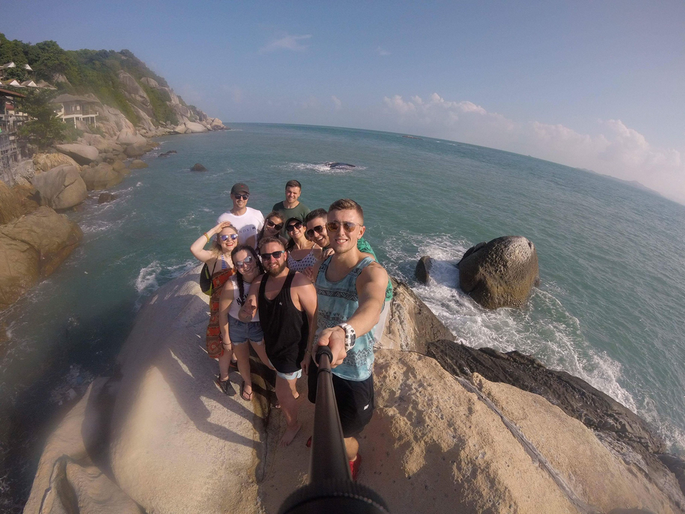 Group of people posing on rocks by the ocean.
