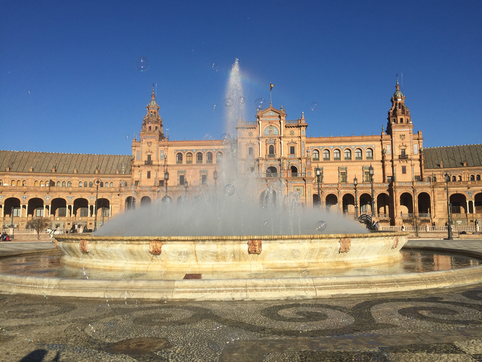 Fountain in front of Spain Square with a historical building in the background.