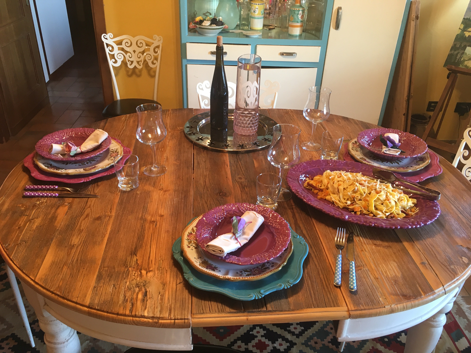 Table de salle à manger garnie de plats colorés et de verres à vin.