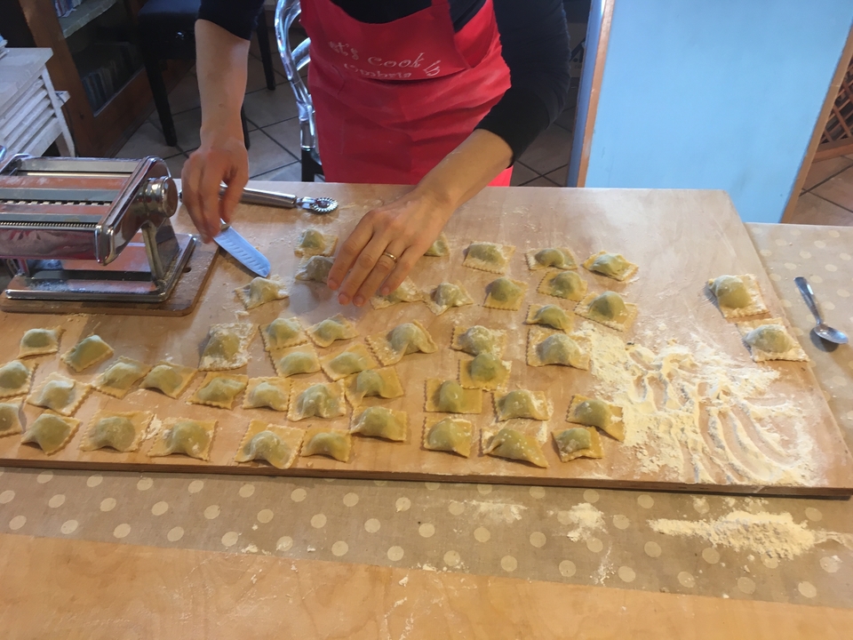 Personne fabriquant des raviolis à la main sur une planche en bois.