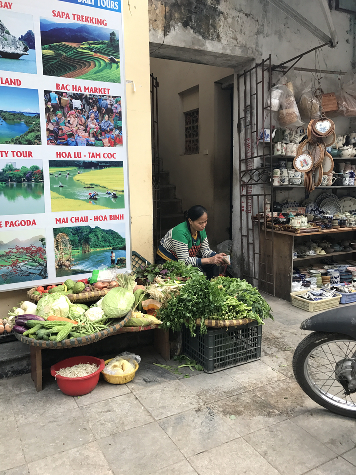 Vendeur sur le marché avec des légumes et un stand de poterie.