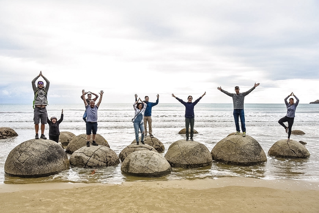 Personnes posant sur de gros rochers sur une plage.