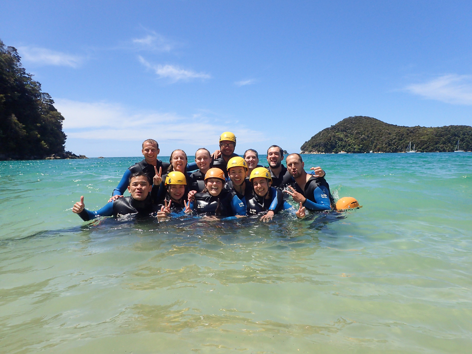 Groupe de personnes en combinaison de plongée dans la mer avec des collines en arrière-plan.