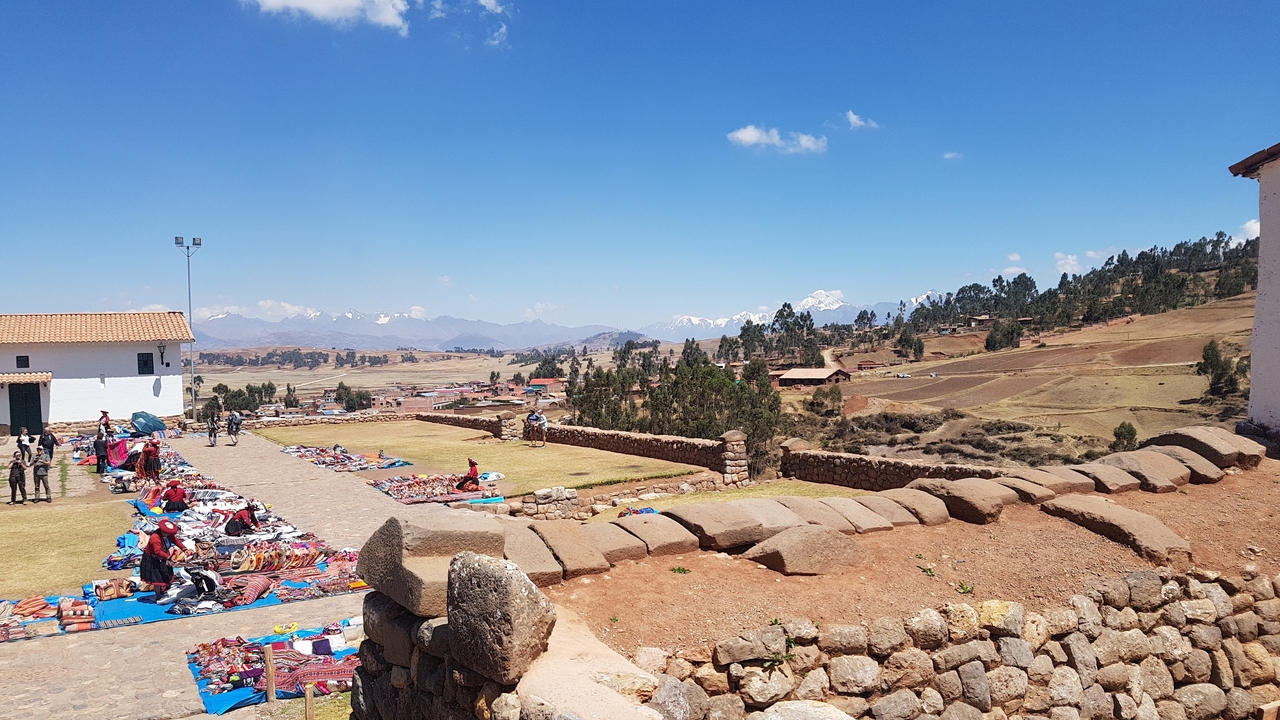 Zone de marché avec des produits textiles et de grandes montagnes en arrière-plan.