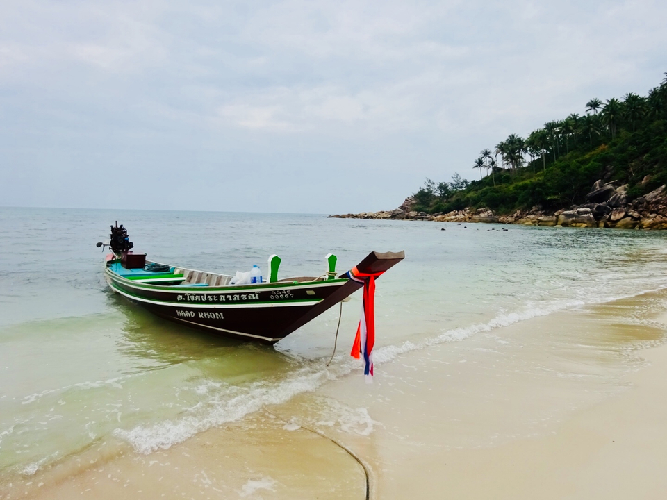Colorful longtail boat on a beach with tropical scenery.