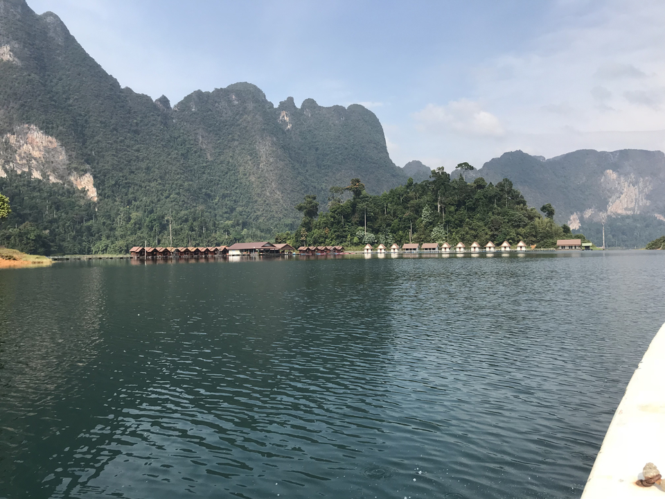 Floating bungalows on a placid lake with lush green hills.