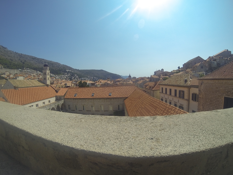 View of a historic town with terracotta rooftops and hills in the background.