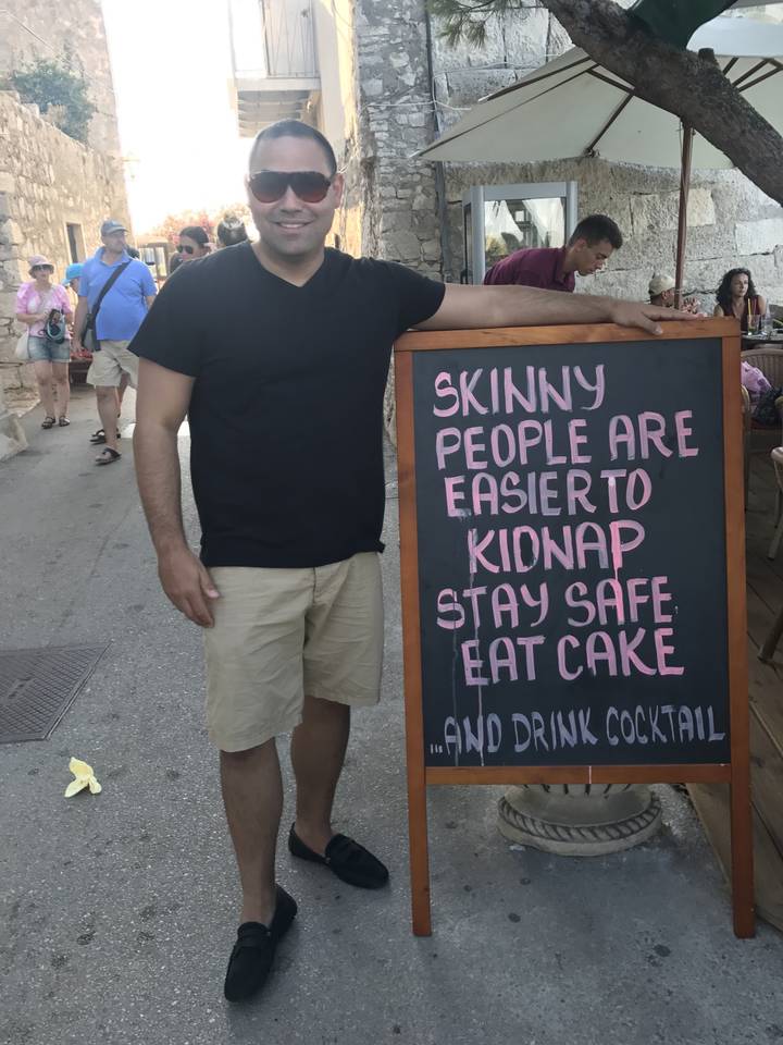 Homme posant à côté d'un panneau humoristique