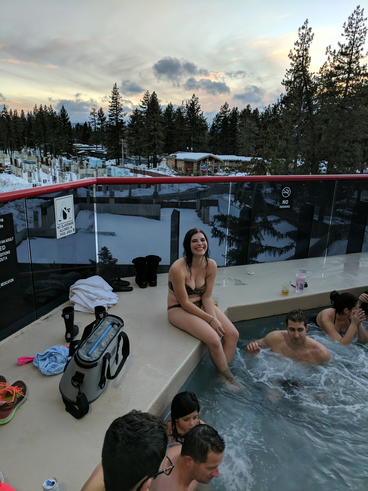 Femme souriante dans un jacuzzi avec de la neige en arrière-plan.