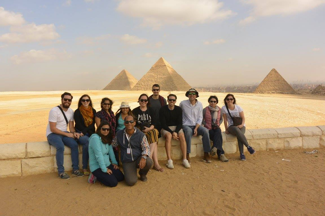A group posing with the pyramids in the background.