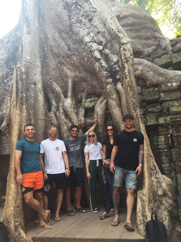 Group of friends posing amongst tree roots and ancient ruins.