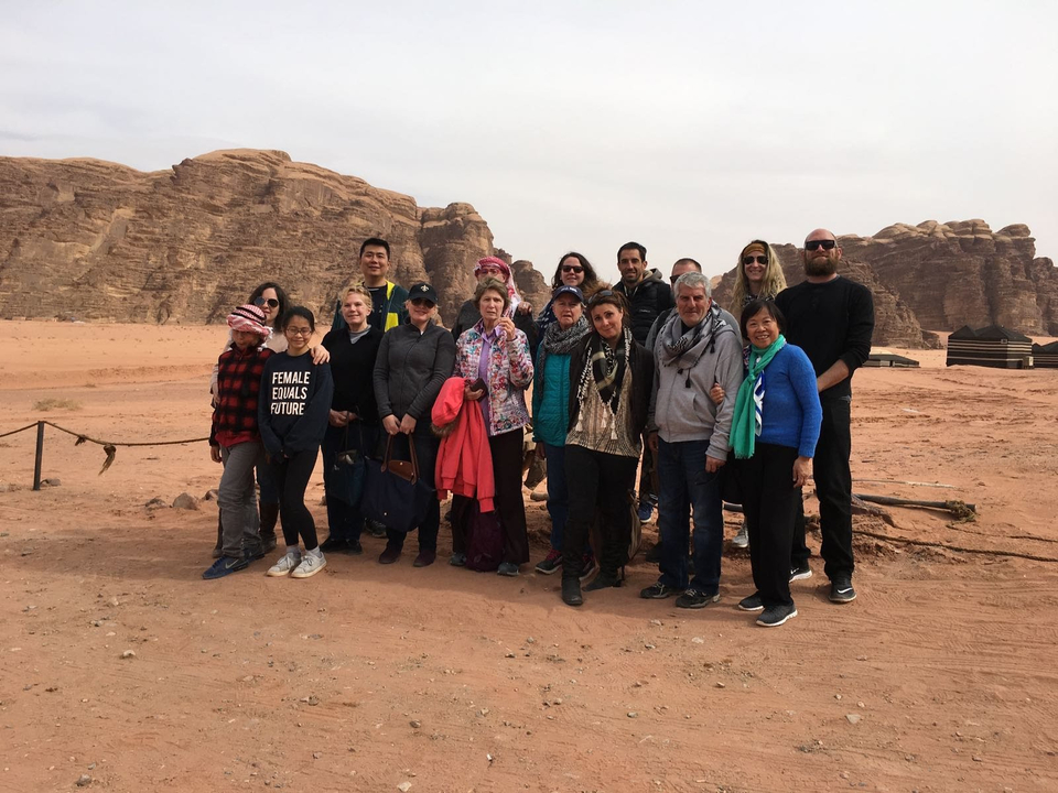 Group posing in a desert landscape with rock formations.