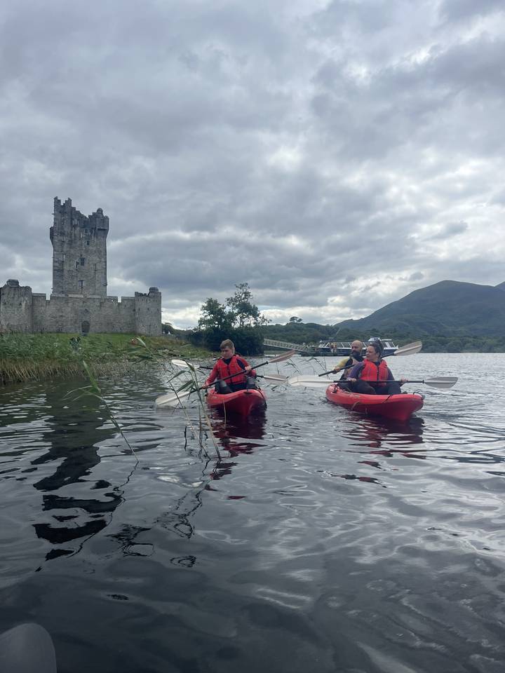 Kayakers on a lake with a historical structure in the distance.