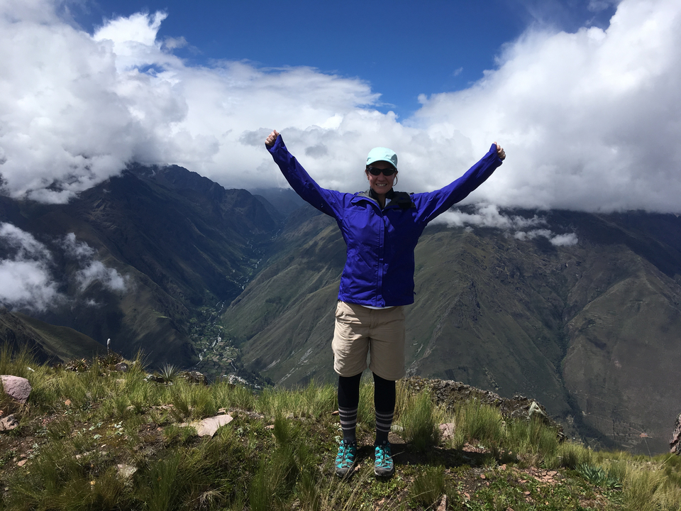 Personne posant joyeusement au sommet d'une montagne.