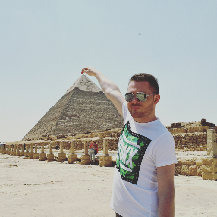 Homme pinçant avec humour le sommet d'une pyramide.