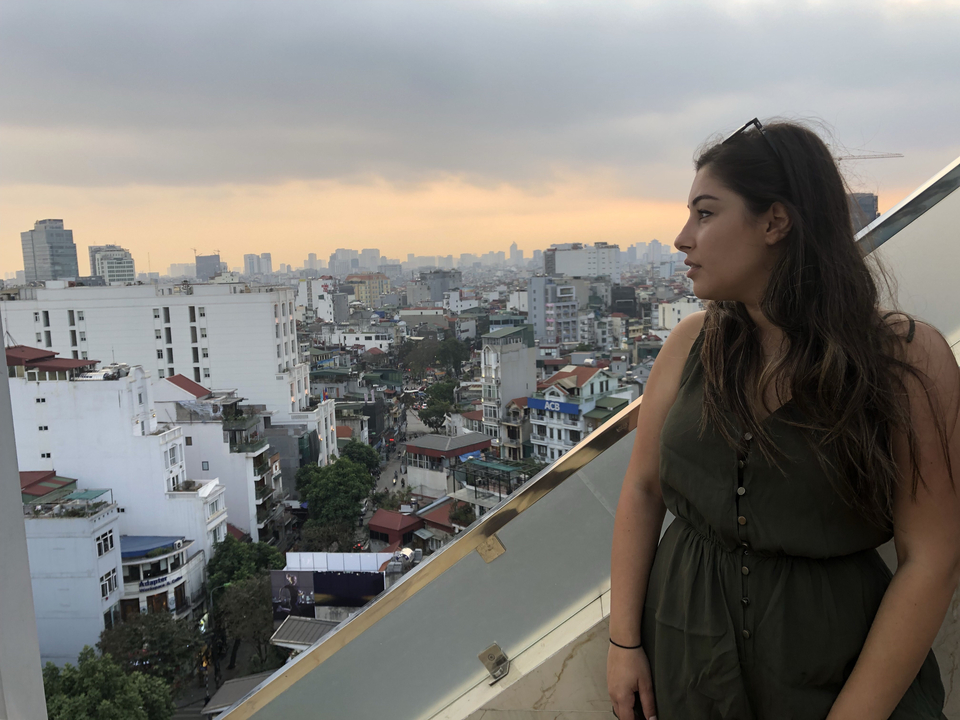 Personne sur un toit avec vue sur la ville au coucher du soleil.