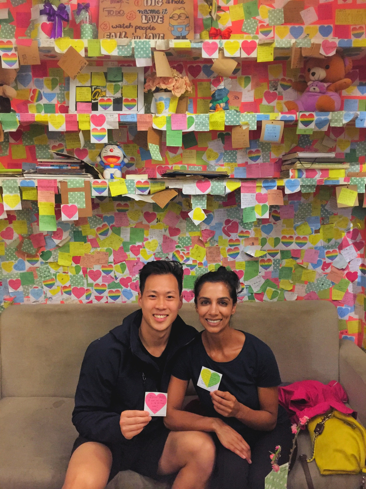 Deux personnes avec un mur coloré couvert de notes et un jouet.