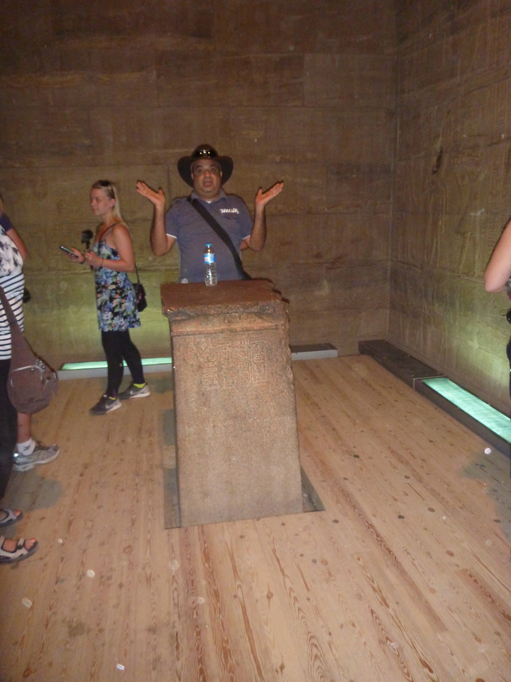 Des personnes observant un piédestal historique à l'intérieur d'une structure ancienne.