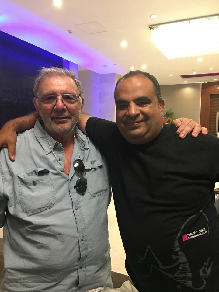 Deux hommes posant à l'intérieur, les bras enlacés.