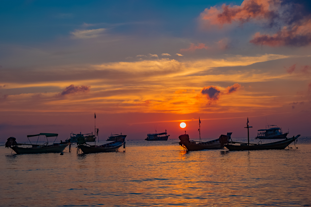 Boats on the sea with a vibrant sunset.