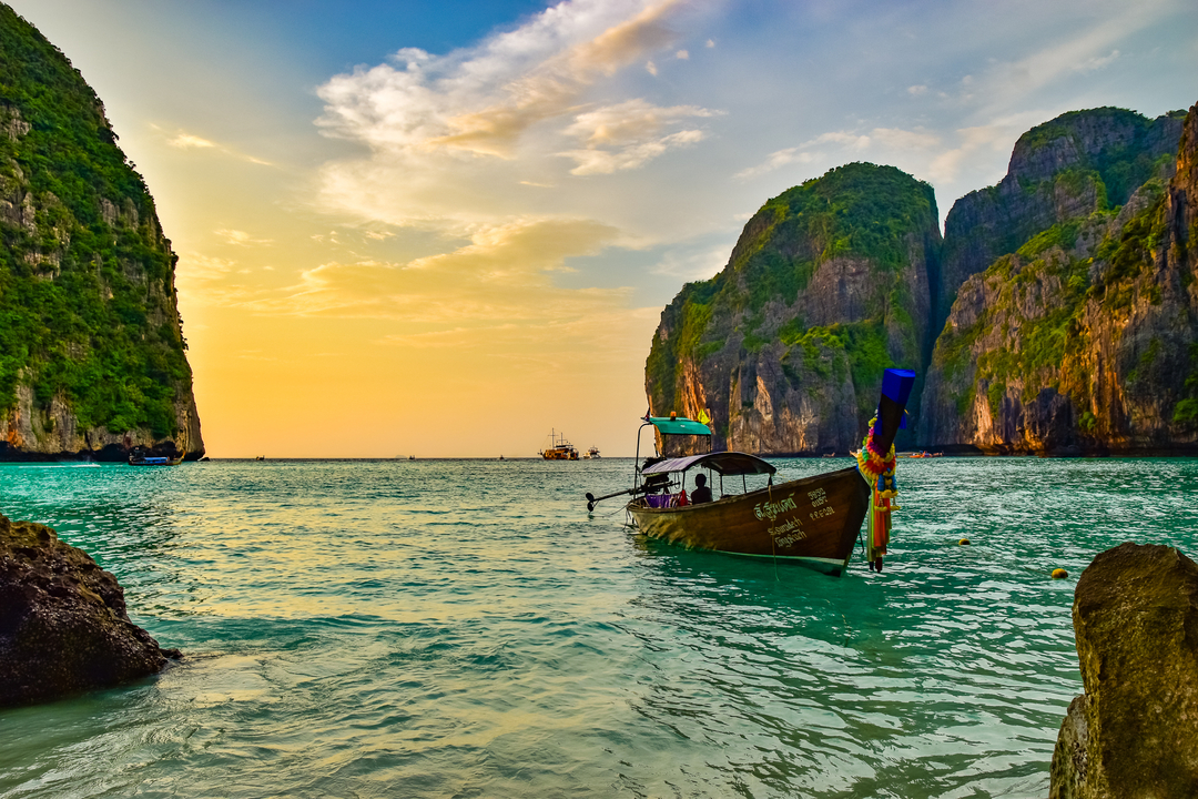 Traditional long-tail boat in turquoise waters surrounded by cliffs.