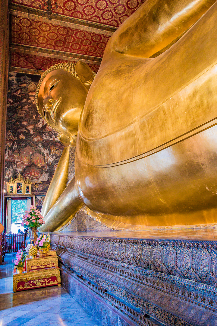 Partial view of a gold statue with intricate wall art.