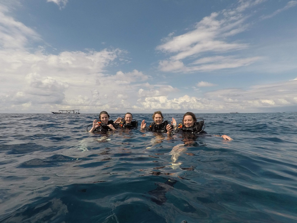 Group of divers in the ocean holding underwater cameras.