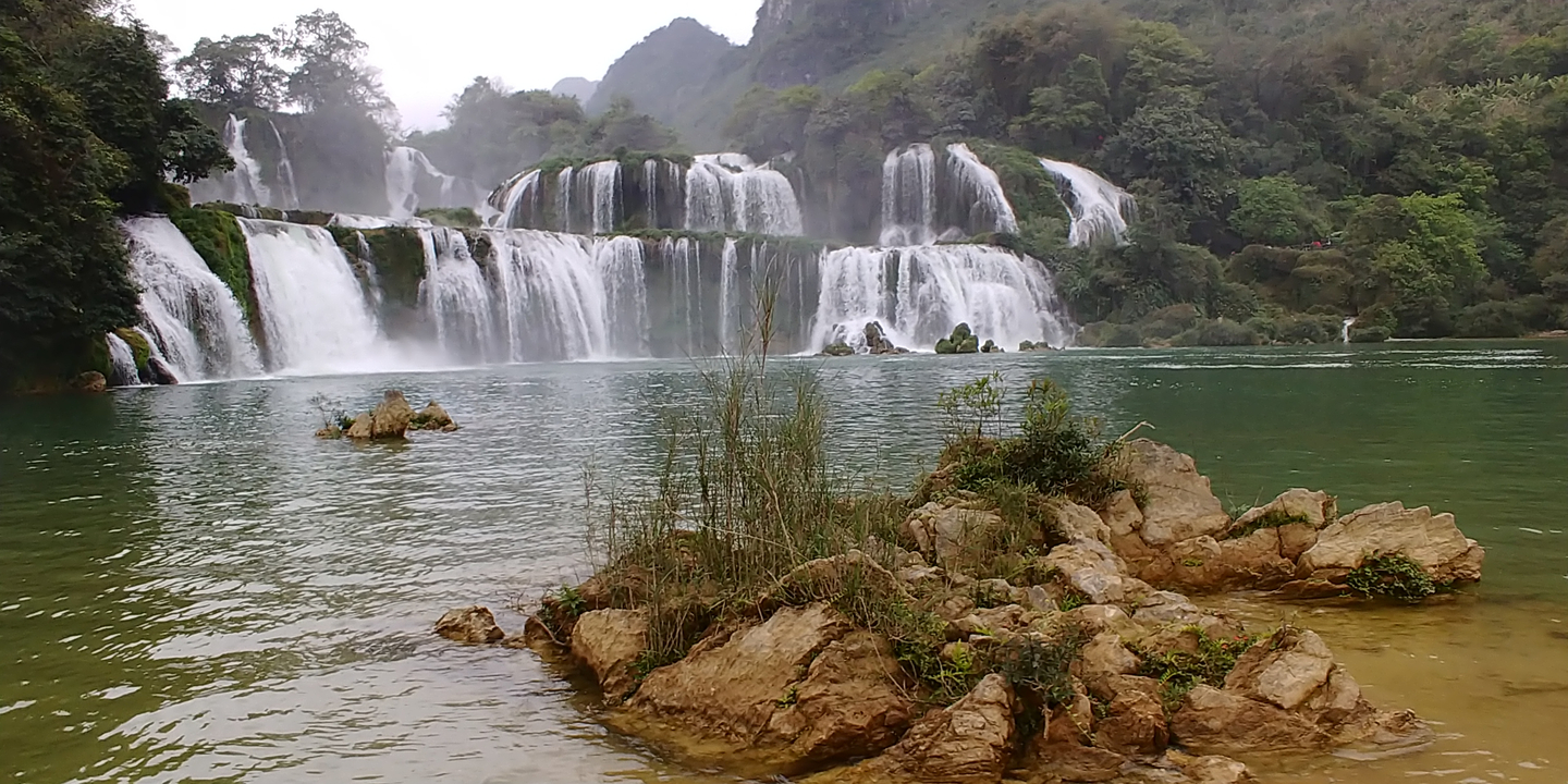 Une belle vue d'une cascade avec des rochers et de la verdure.