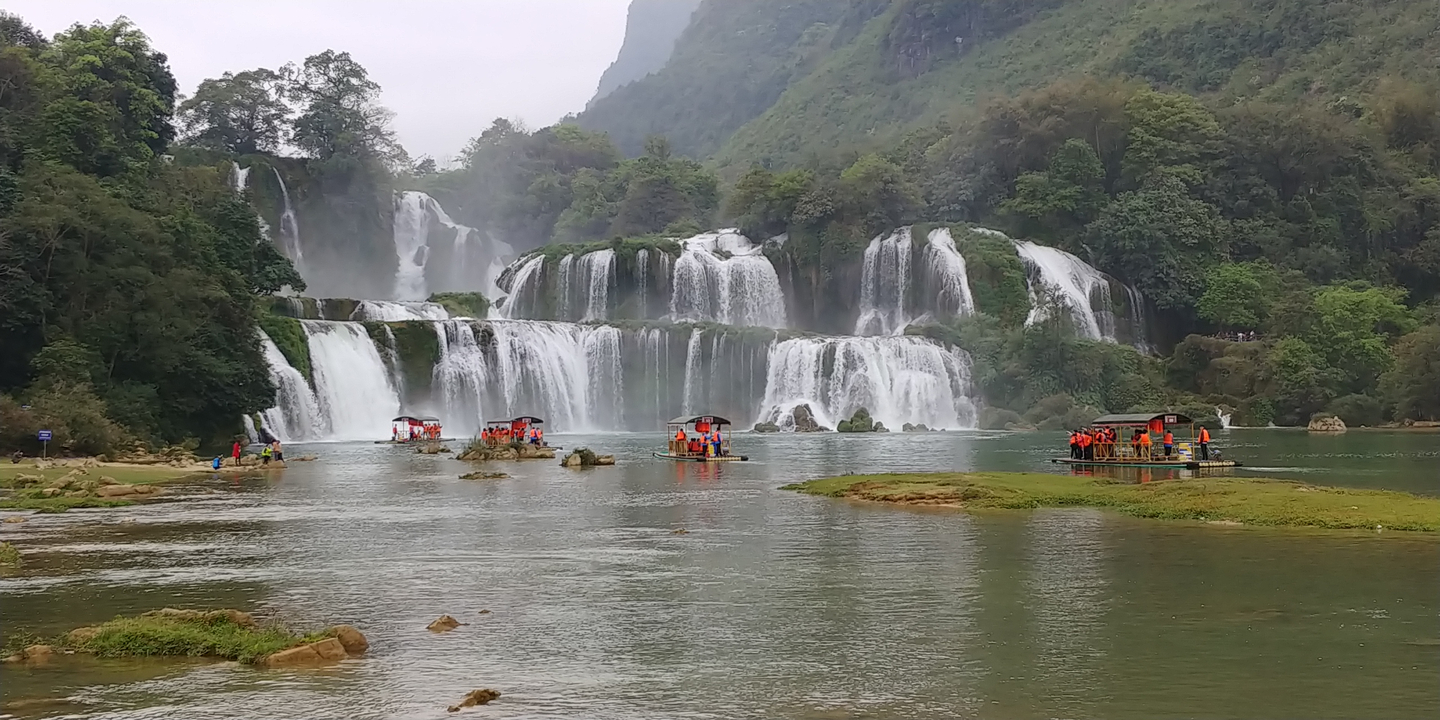 Une chute d'eau étonnante avec des personnes sur des radeaux au premier plan.