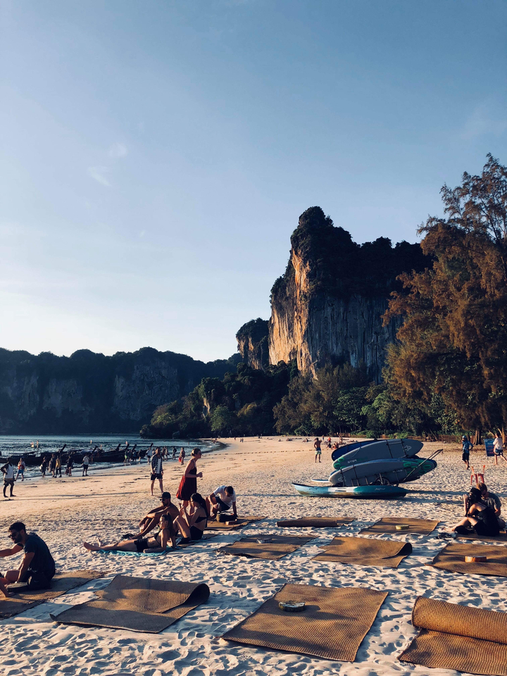 A beach with towering cliffs and people jogging and playing.