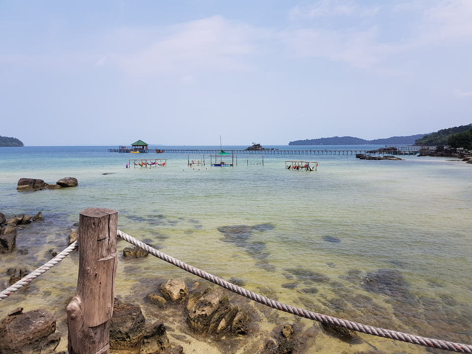 A beautiful seaside view with a pier and hammocks.
