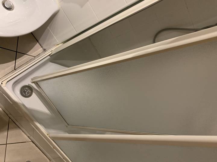 Coin d'une cabine de douche avec un mur carrelé.