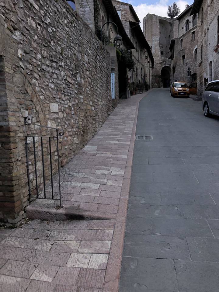 Rue pavée dans une ville historique avec des bâtiments en pierre.