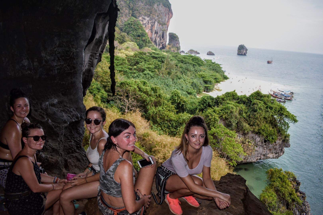 Group of people seated on a cave ledge overlooking the coast.