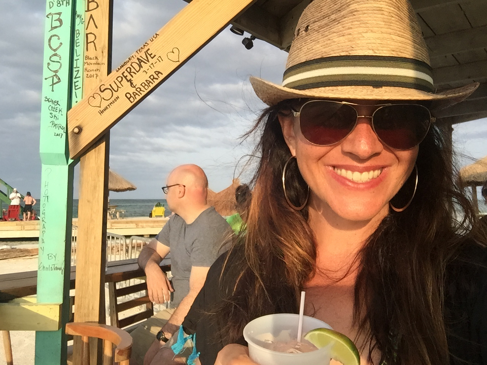 Personne souriant avec un chapeau par une journée ensoleillée.