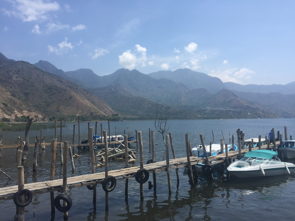 Quai avec bateaux et montagnes en toile de fond.