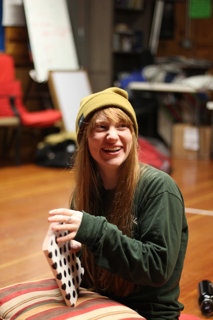 Une personne souriant à l'intérieur, portant un bonnet jaune.