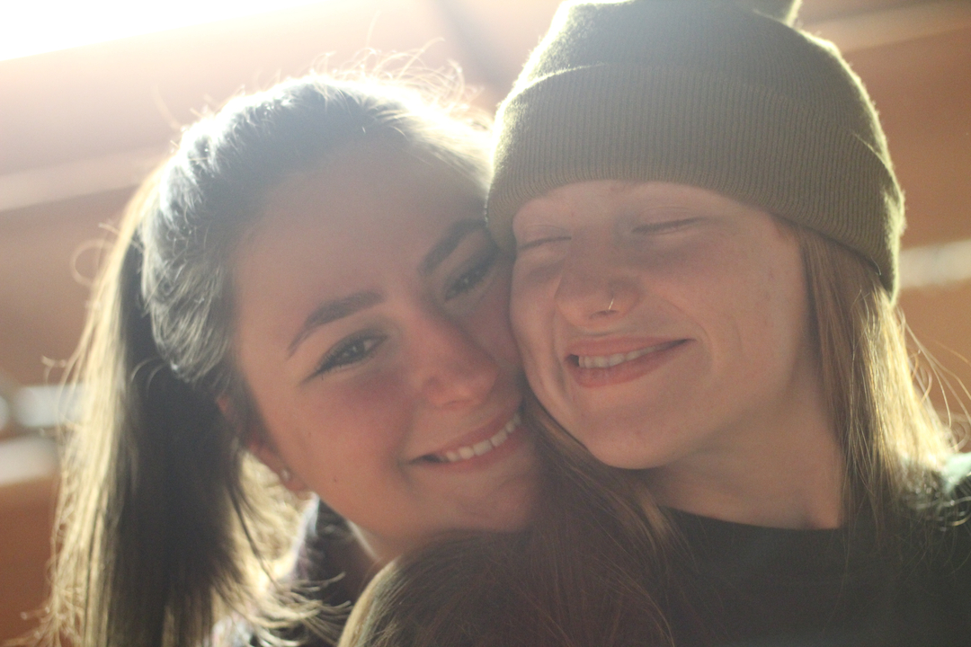 Deux personnes proches l'une de l'autre à l'intérieur, souriantes.