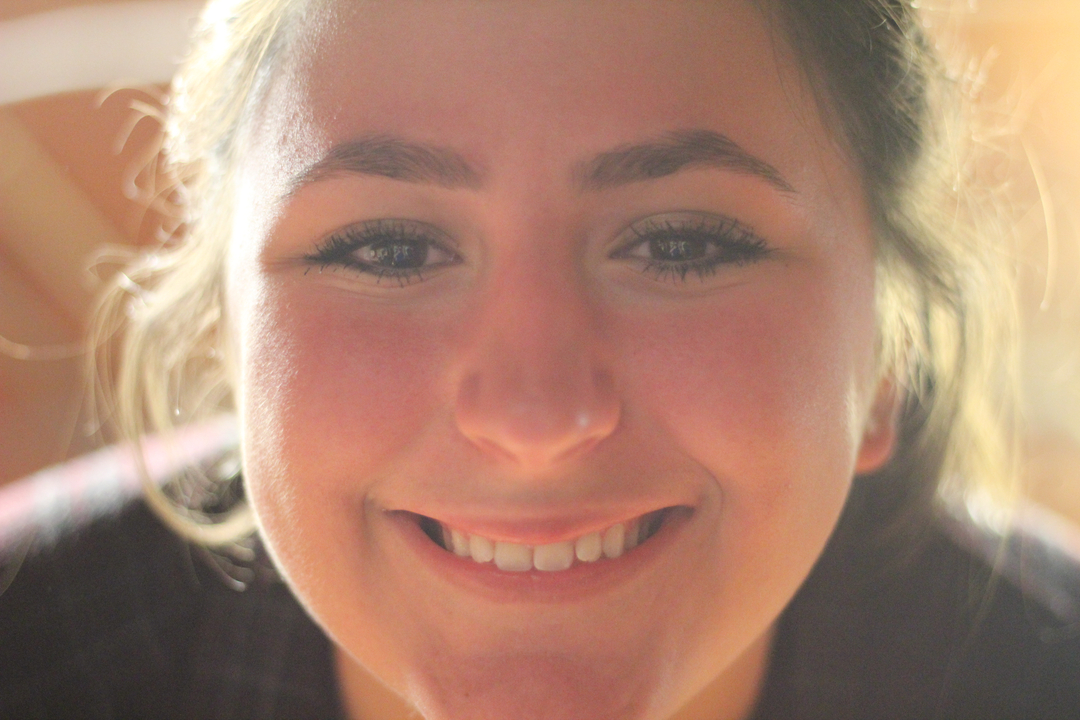 Gros plan d'une personne souriant à l'intérieur.