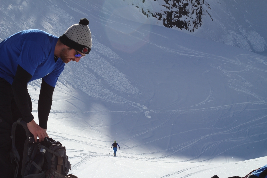 Une personne préparant son matériel avec une pente enneigée en arrière-plan.
