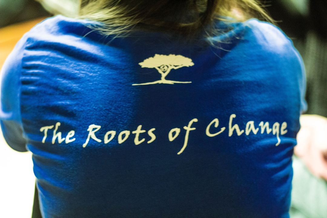 Vue de dos d'une chemise bleue portant l'inscription "The Roots of Change".