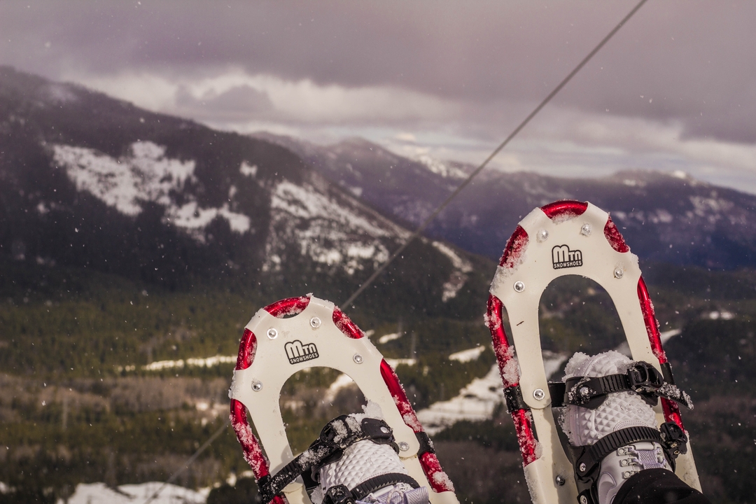 Raquettes à neige au premier plan et montagnes enneigées au loin.