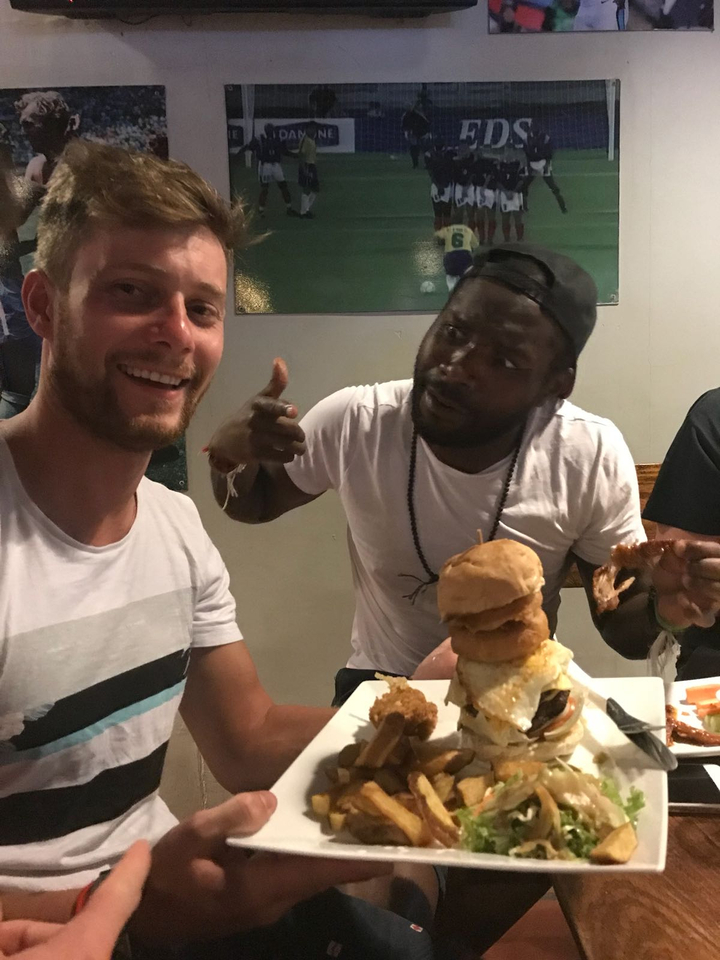 Two people enjoying a meal indoors, one showing a thumbs up.