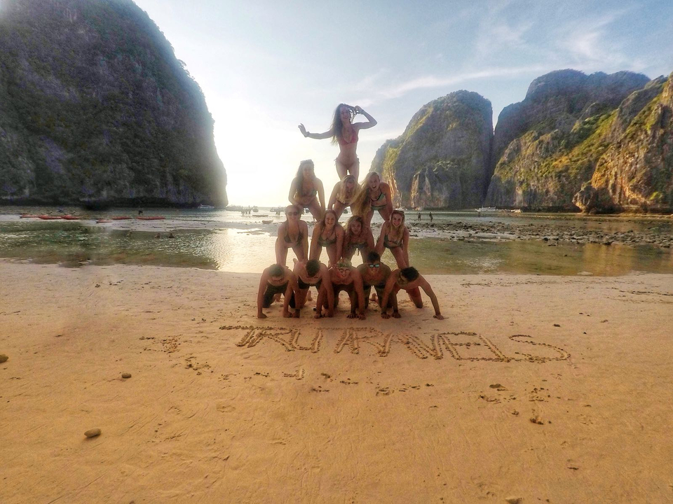Group forming a human pyramid on the beach.