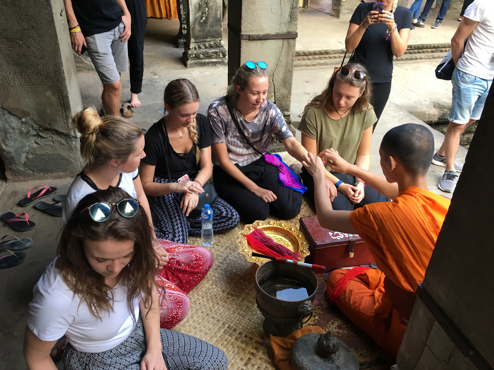 Groupe assis autour d'un moine dans un temple, engagé dans une activité.