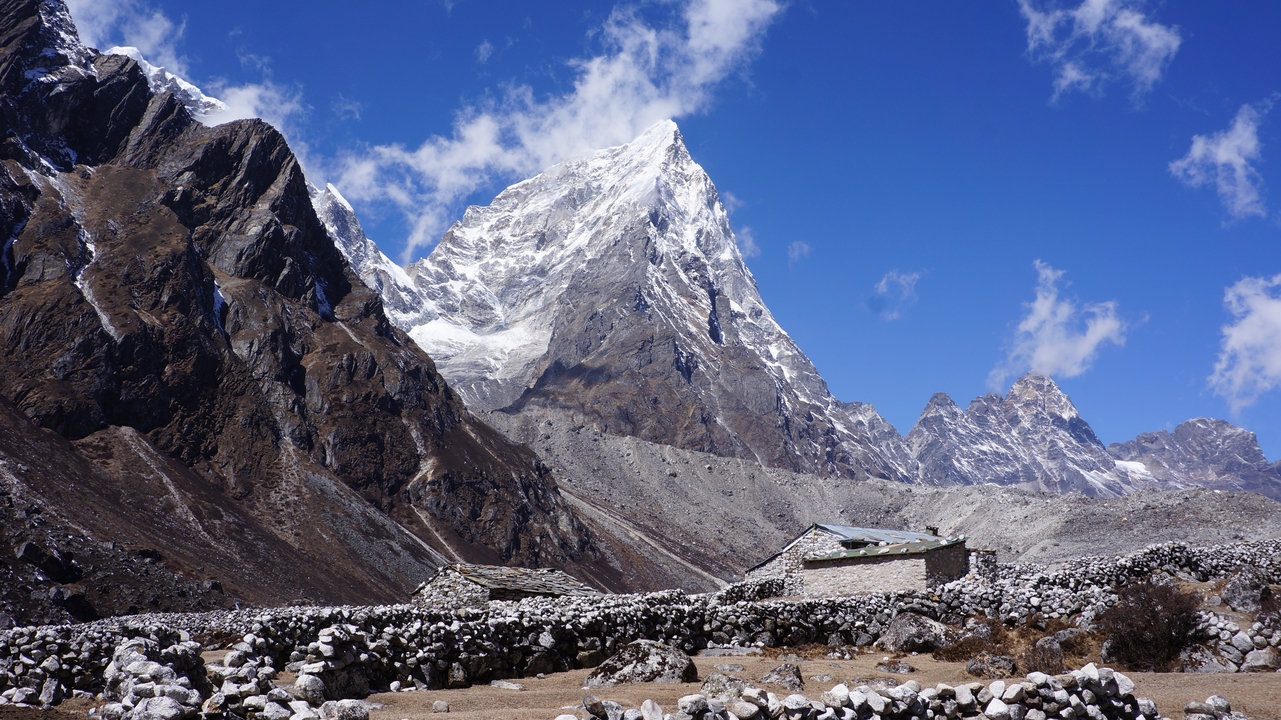 Montagne enneigée avec des maisons en pierre au premier plan.
