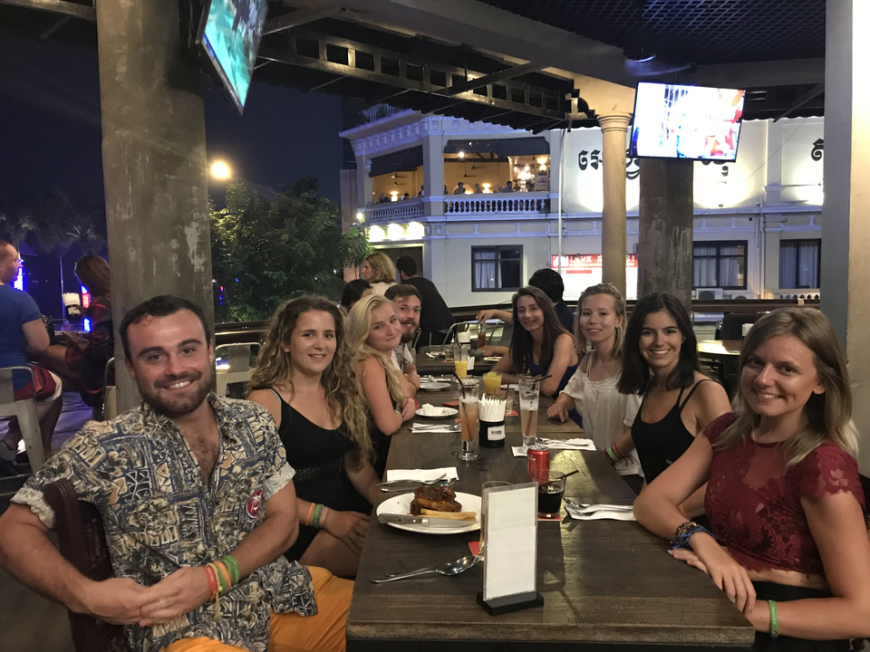 Groupe de personnes assises à une table dans un restaurant le soir.